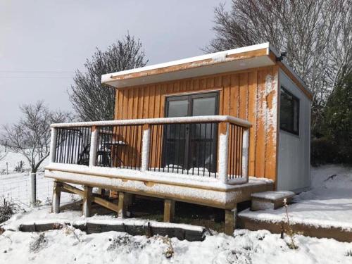Cabaña de madera con banco en la nieve en Lawfield en Glenomaru