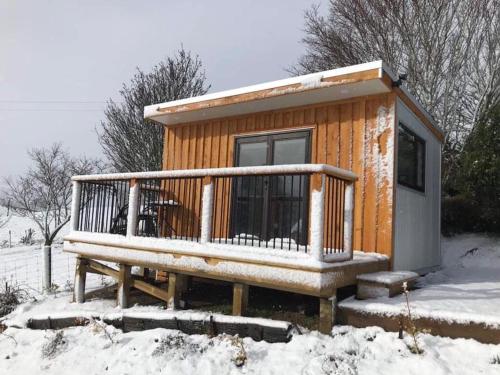 a wooden cabin with a bench in the snow at Lawfield in Glenomaru