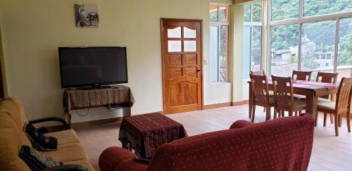 a living room with a television and a table and chairs at Villas JABEL TINAMIT in Panajachel