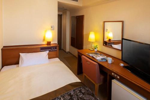 東京にあるチサンホテル浜松町のベッド、デスク、テレビが備わるホテルルームです。