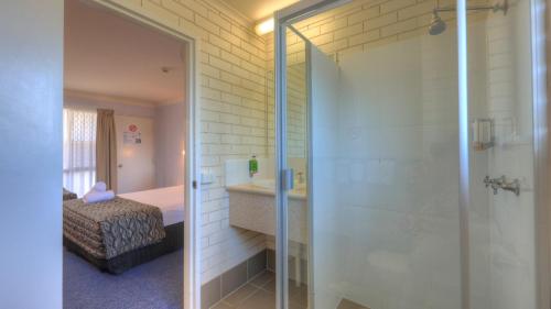 a bathroom with a shower and a sink and a bed at Cleveland Bay Air Motel in Cleveland