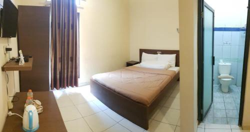 Dormitorio pequeño con cama y aseo en Hotel Sun Q Ta Guci en Tegal