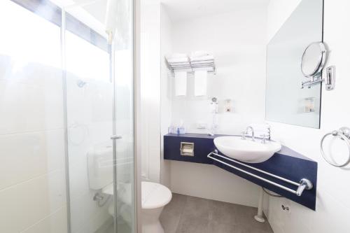 a bathroom with a sink, toilet and bathtub at Airolodge International in Brisbane
