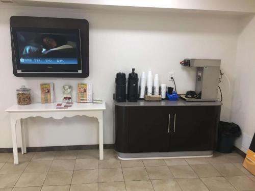 a room with a tv on the wall and a table at Motel 6-Nashville, TN - Airport in Nashville