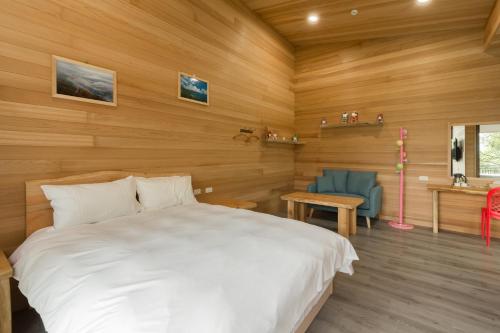 a bedroom with a white bed and a blue chair at Chingjing Abin Minshuku in Renai
