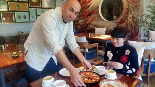 a man serving a child a pizza on a table at Li River Resort in Yangshuo