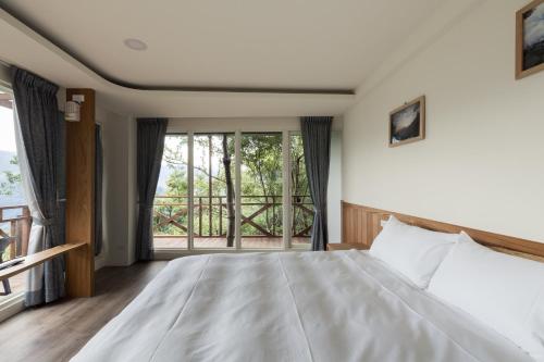 a bedroom with a large bed and a window at Chingjing Abin Minshuku in Renai