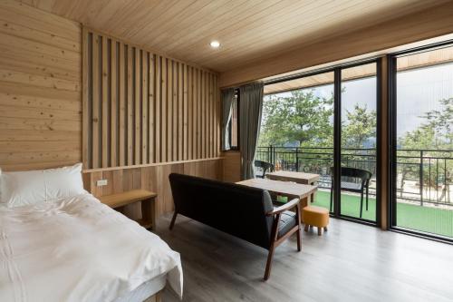 a bedroom with a bed and a desk and a table at Chingjing Abin Minshuku in Renai