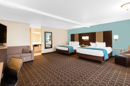 a hotel room with two beds and a couch at Travelodge by Wyndham Angels Camp CA in Angels Camp