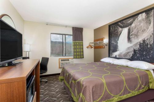 a hotel room with a bed and a flat screen tv at Super 8 by Wyndham Dubois in Dubois
