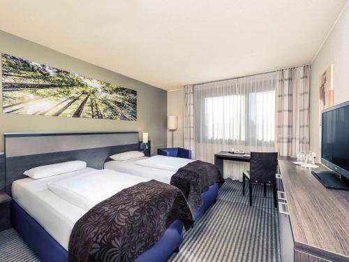 ラーティンゲンにあるメルキュール デュッセルドルフ エアポートのベッド2台とデスクが備わるホテルルームです。