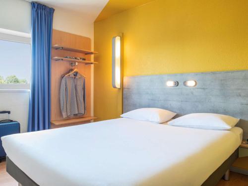a bedroom with a white bed and a yellow wall at ibis budget Grigny Centre in Grigny