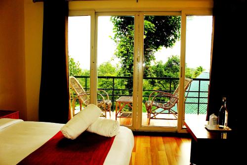 1 dormitorio con cama y vistas a un balcón en Bellavista Resort Munnar, en Munnar