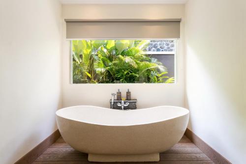 a bath tub in a bathroom with a window at Annupuri Villas Bali in Canggu