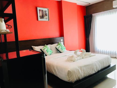 two swans sitting on a bed in a red bedroom at Thanks​Pama​ in Bang Khen