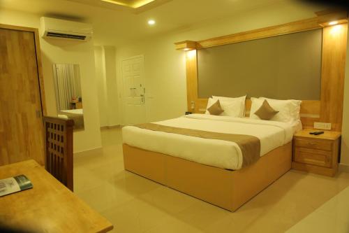 a bedroom with a large bed and a bathroom at The Hotel Chettungal in Angamaly