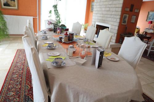 a long dining table with white chairs and a table cloth at B&B La Maison de L'Aubette in Magny-en-Vexin