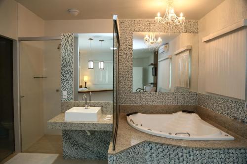 a bathroom with a tub and a sink and a mirror at Monte Castro Executive Hotel in Araguari