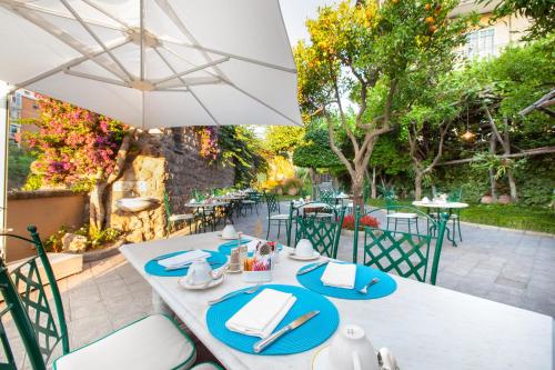 a white table with blue plates and an umbrella at Hotel Antiche Mura in Sorrento