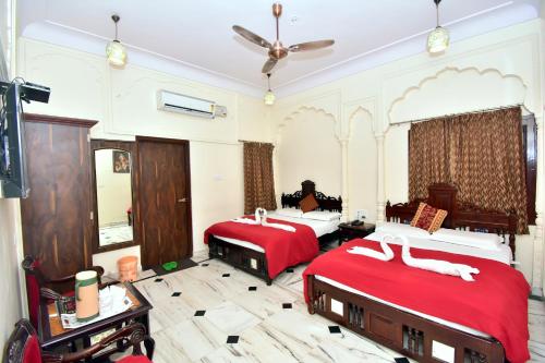 a bedroom with two beds and a ceiling fan at Hotel Kalyan in Jaipur