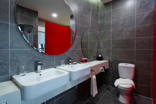 a bathroom with two sinks and a mirror and a toilet at Qliq Damansara Hotel in Petaling Jaya