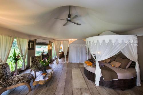 a bedroom with a bed and a ceiling fan at Sandat Glamping Tents in Ubud