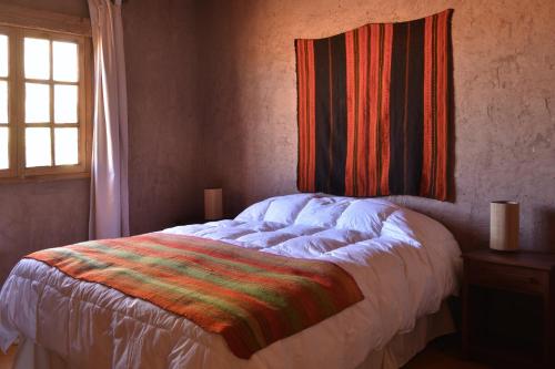 Un dormitorio con una cama con una manta de colores. en Casas Valle De La Luna, en San Pedro de Atacama