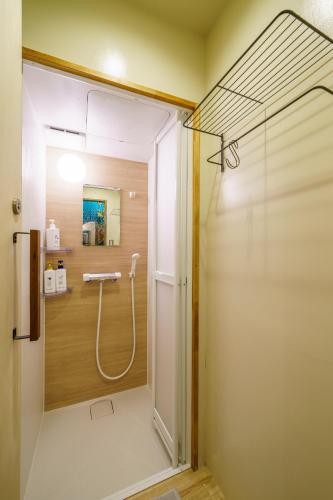 a bathroom with a shower with a glass door at Mad Cat Hostel Osaka & Bar in Osaka
