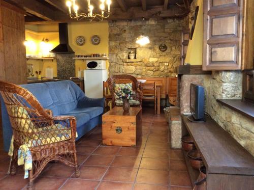 a living room with a blue couch and a kitchen at La Foina in Ceceda de Abajo