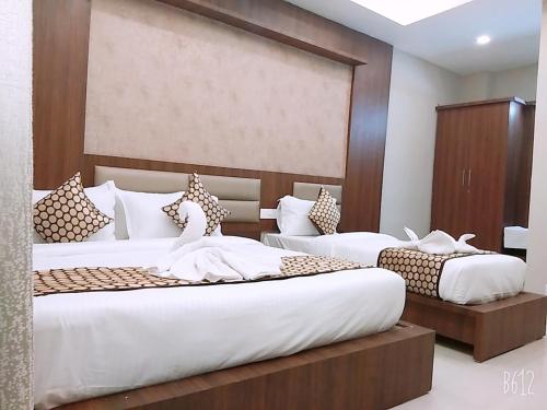 two beds in a hotel room with white sheets at Grand Oliver in Chennai