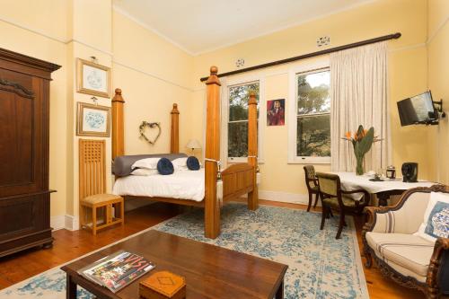 a living room with a bed and a table at Royston Hall Historical Guesthouse in Umtentweni