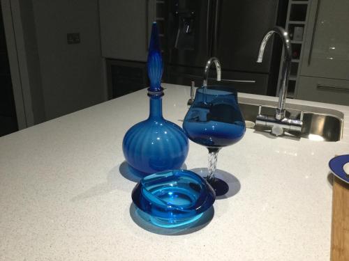 eine blaue Glasvase und ein Glas Wein auf der Theke in der Unterkunft Five Oaks in Derry Londonderry