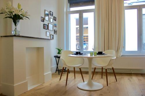 une table et des chaises blanches dans une chambre avec fenêtres dans l'établissement Bennestay, à Gand