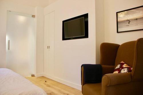 a bedroom with a couch and a television on the wall at Bennestay in Ghent