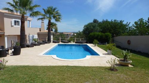 a swimming pool in a yard with palm trees at VILLA L'ESTAQUE in Armação de Pêra