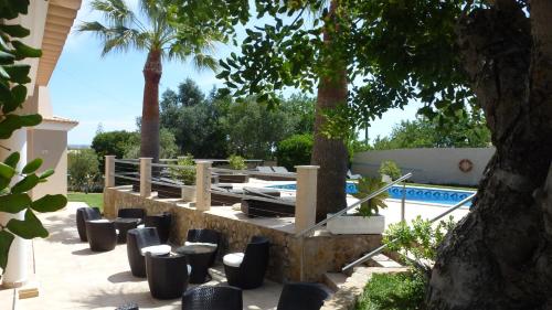 a patio with chairs and a pool with palm trees at VILLA L'ESTAQUE in Armação de Pêra