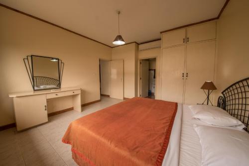 a bedroom with a bed and a desk and a mirror at Speke Hotel 1996 Ltd in Kampala