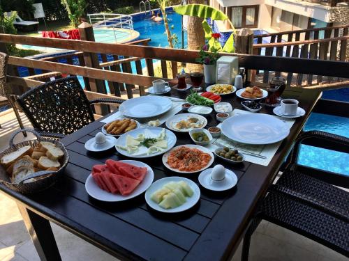 a table with plates of food on a table near a pool at Alya Hotel Göcek in Göcek
