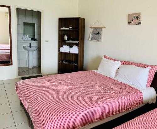 a bedroom with a bed with a red and white blanket at Puli Islet Inn in Puli