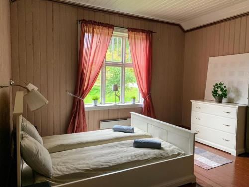 a bedroom with a bed with red curtains and a window at vrangfoss slusevokterbolig in Funnemark