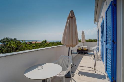 a balcony with a table and an umbrella at Hotel Manora in Nerezine