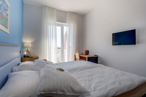 a bedroom with a large white bed with a window at Hotel Manora in Nerezine