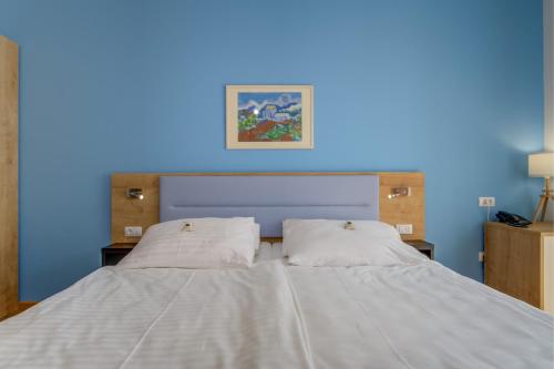 a blue room with a bed with two white pillows at Hotel Manora in Nerezine