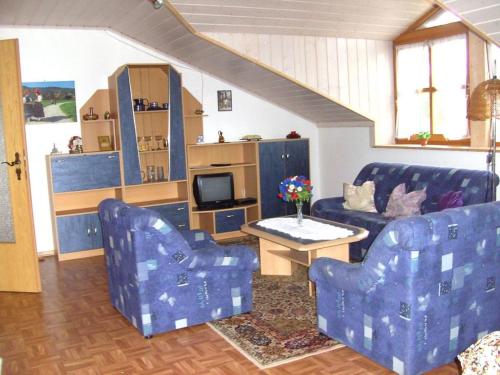 a living room with two blue chairs and a tv at Ferienwohnung Oblfing in Schöllnach