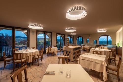 un restaurante con mesas, sillas y ventanas en Il Vigneto, en Roddi