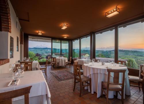 a restaurant with tables and chairs and large windows at Il Vigneto in Roddi