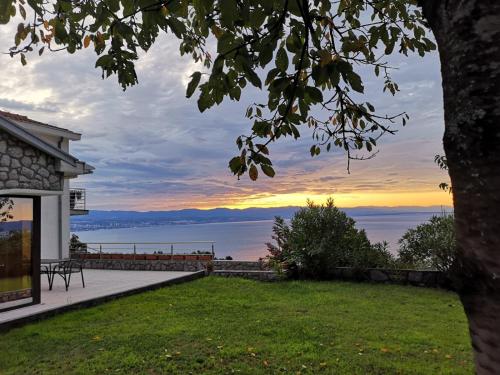 a house with a view of the ocean at sunset at Apartments Villa Cerić in Lovran