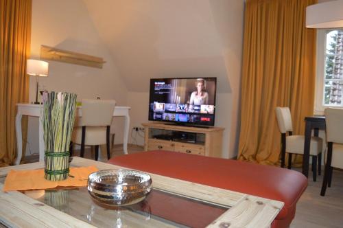 a living room with a television and a table at Landhaus Zum Heidewanderer mit THERMEplus in Bad Bevensen