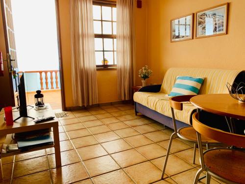 een woonkamer met een bank en een tafel bij Apartamentos Isla Encantada in Puntallana