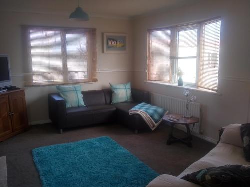 a living room with a couch and a table and windows at sunrise view in Trimingham